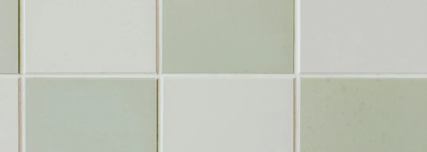 Reticolo regolare delle fughe fra piastrelle quadrate verde salvia e bianco
